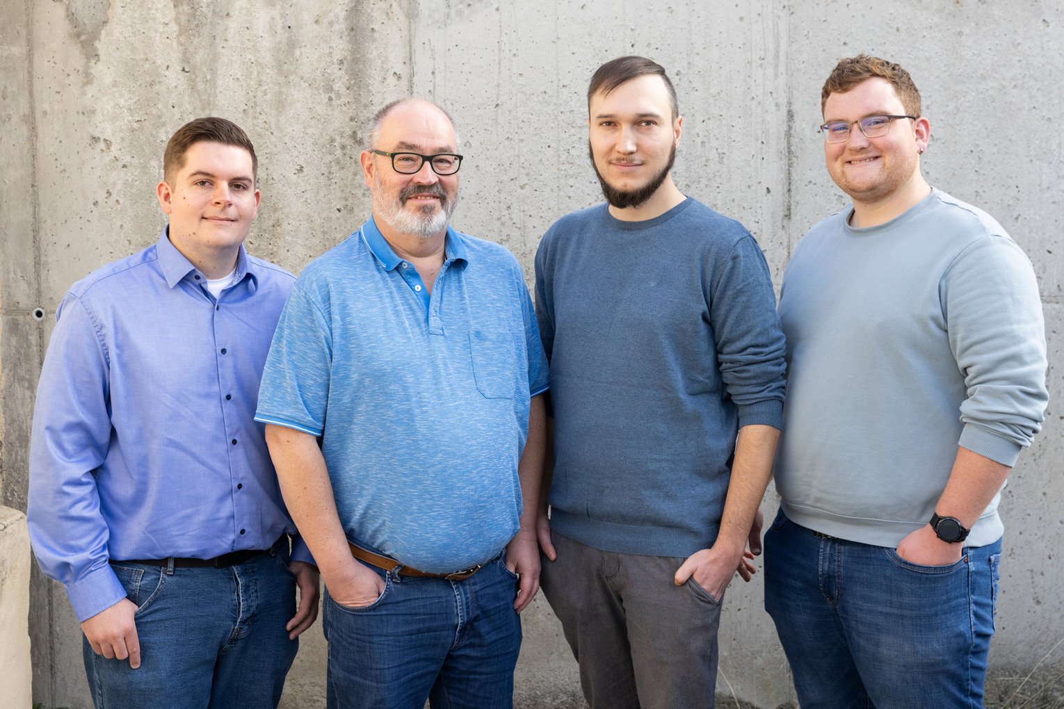 Das Managed Service Team von all for IT steht vor einer Betonwand